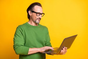 web designer near me | man holding a laptop againsta a yellow background