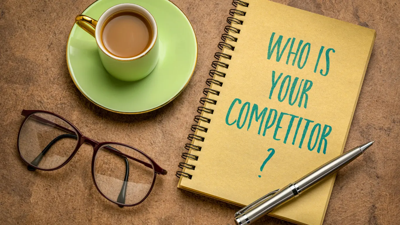 A book with the title  'who is your competitor?', a cup of tea and glasses