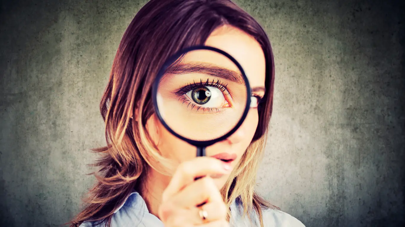 Woman with magnifying glass symbolising looking into SEO competitor analysis