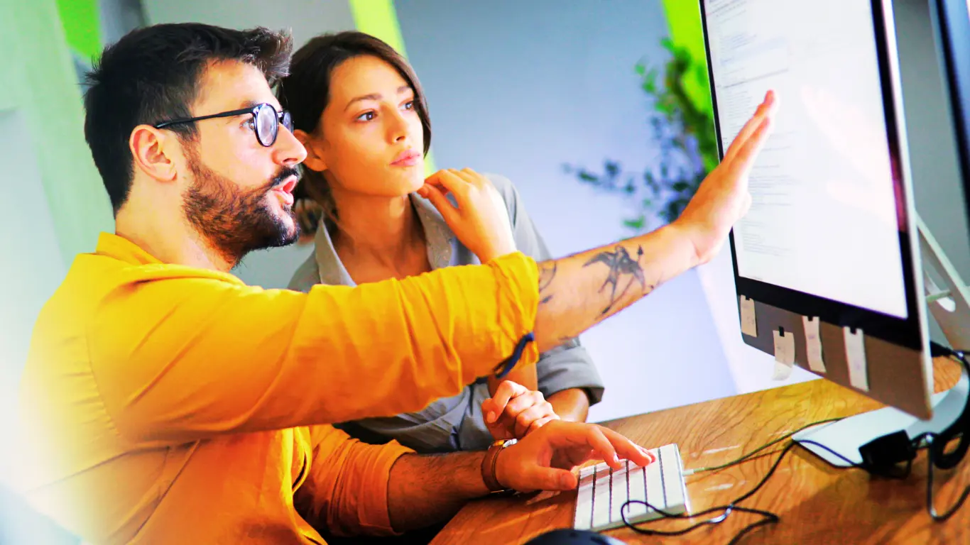 Two people at a computer integrating keyword research and competitor analysis