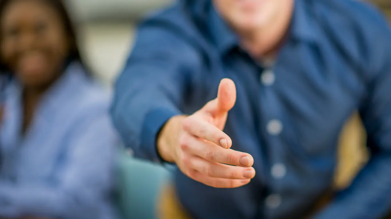 man in a blue shirt reaching his hand out to shake hands