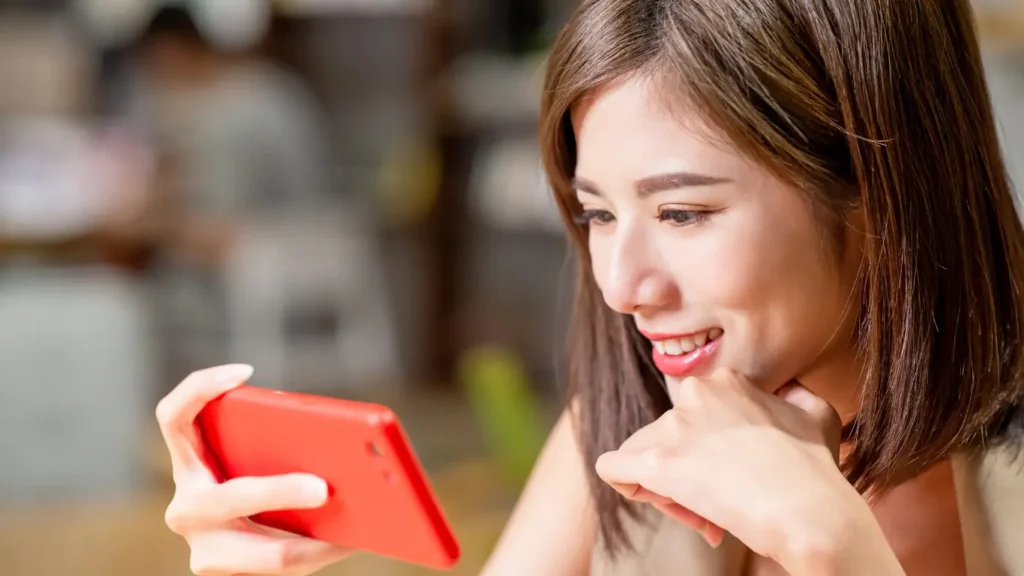 female watching video content on a red smart phone