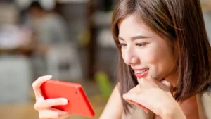 female watching video content on a red smart phone