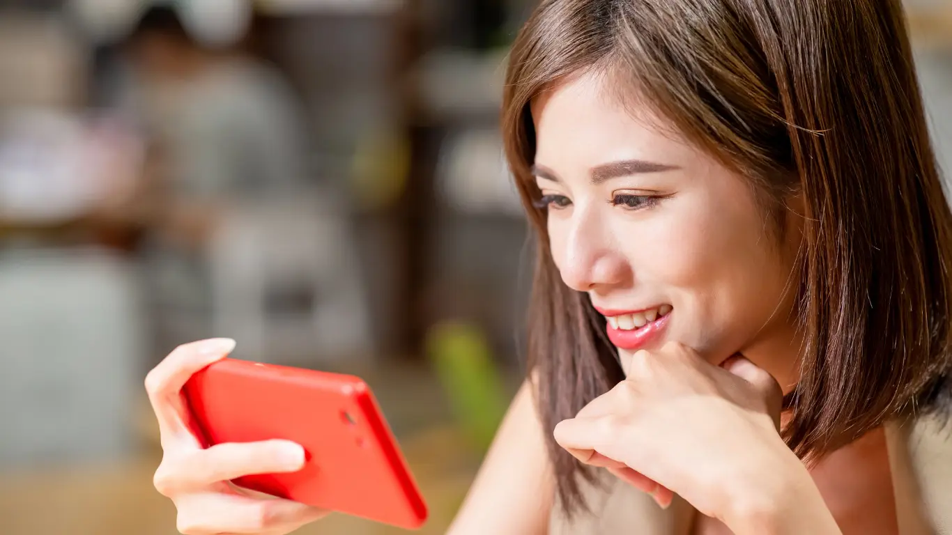 female watching video content on a red smart phone